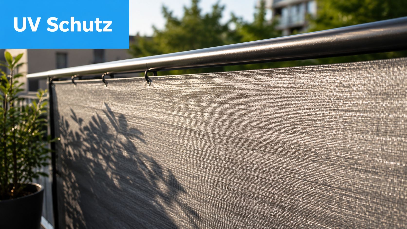 Stoff mit glänzender Oberfläche: Ihr Balkon-Sichtschutz 4 Ein grauer Stoff mit glänzender Oberfläche als Sichtschutz an einem schwarzen Balkongeländer mit pflanzlichem Schattenwurf.